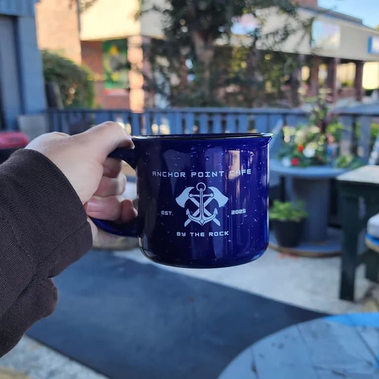 A blue Anchor Point Cafe mug on the patio